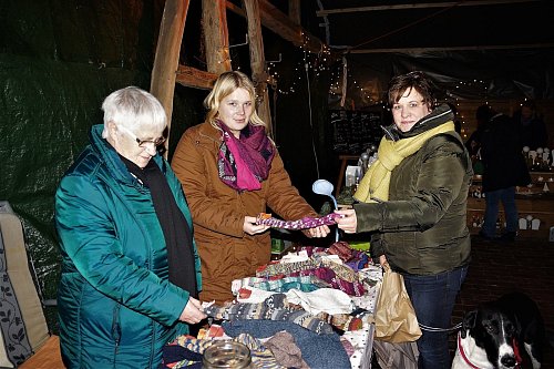 Für die kalte Jahreszeit: Irma Wacker (von links) und Enkelin Jana Schlöpker haben selbst gestrickte Socken im Angebot. Andrea Balzar stöbert interessiert im vielfältigen Sortiment. - © Marion Bulla