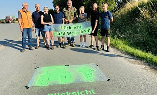 Radfahrervorstand Ekkehard Härtel und Norbert Rieks vom ADFC, Landjugendmitglieder sowie die Ortslandwirte Hannes Dicke-Wentrup und Jürgen Schierenbeck präsentieren das erste Asphaltbild vor der Gerätehalle Temming. - Herbert Gontek
