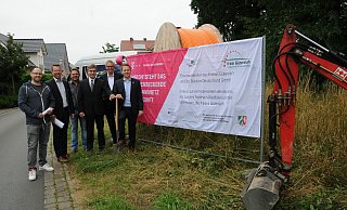 Unübersehbar: Auf dem Schild an der Jägerstraße wird erklärt, wer da was baut. Vitali Saprykin (Stadt), Fachbereichsleiter Dirk Niggemann, Bauunternehmer Thomas Görzen, die beiden Telekom-Vertreter Gregor Vos und Klaus Karneth sowie Bürgermeister Michael Meyer-Hermann tätigen den symbolischen ersten Spatenstich. - Tasja Klusmeyer, HK