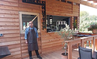 Rolf Zurmühlen, Chef des gleichnamigen Gasthofs in Borgholzhausen, bietet rund 80 Plätze im Biergarten an, der hier Sommergarten heißt. Hier steht er vor der "Winkelshütte", in der für die Außengastronomie Gerichte gekocht und Getränke gezapft werden. - Claus Meyer