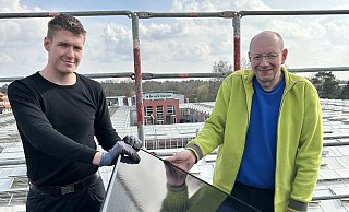 Auszubildender Alex Penner und Elektroniker-Meister Jörg Hoffmann installieren ein PV-Modul auf dem Dach des Brockmeyer-Cafés. - Tobias Barrelmeyer