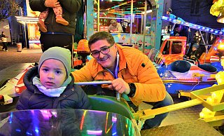 Vjekoslav Paradzik hat seinen Enkel Malik (2) auf den Sitz des Kinderkarussells gehoben. - Ekkehard Hufendiek