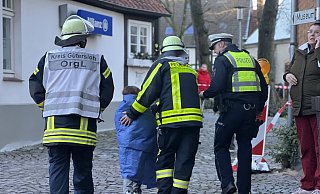 Feuerwehrmänner führen eines der in den Gondeln sitzenden Kinder in einer Decke gehüllt Richtung Kirchplatz. Dort konnten sich die Fahrgäste des Kettenfliegers aufwärmen und ärztlich untersuchen lassen. - Paul Brinkmann