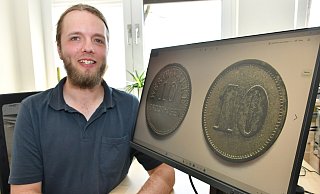 Steinhagens Archivar Patrick Tarner präsentiert zwei der Münzen aus dem Brockhagener Gefangenen-Lager. Diese liegen im Stadtmuseum im Münster. - Jonas Damme