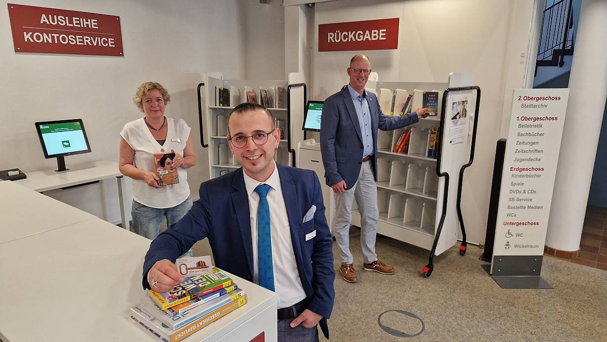 Birgit Schlüter (Bücherei, v.l.), Salih Öztürk (Bibliotheksleiter) und Bürgermeister Thomas Tappe präsentieren die automatisierte Ausleihe und Rückgabe der Medien. | © Uwe Pollmeier