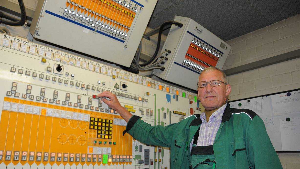 Im Herz des Betriebes: Lagermeister Eckhard Wacker – seit 37 Jahren im Betrieb – steuert die Warenströme und Maschinen. Die älteren technischen Anlagen werden per Knopfdruck über diese Tafel bedient, die neuen per Computer. | © Marc Uthmann,  HK