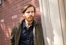 Ein Mann lehnt nachdenklich an einer Hauswand - Christin Klose/dpa-tmn