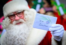 Weihnachtsmann hält Weihnachtspost hoch - Patrick Pleul/dpa/dpa-tmn Weihnachtsmann hält Weihnachtspost hoch - Patrick Pleul/dpa/dpa-tmn