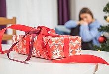 Ein Geschenk auf dem Tisch - eine Frau im Hintergrund - Christin Klose/dpa-tmn