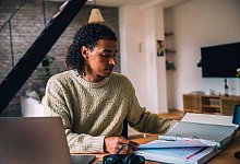 Ein Mann vor einem Aktenordner und einem Laptop - Zacharie Scheurer/dpa-tmn