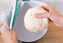 Frau hält einen Hefeteig in der Hand - Florian Schuh/dpa-tmn