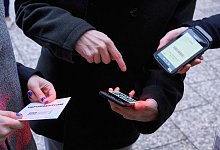 Ein Mann zeigt auf einen QR-Code den eine Frau Scannt - Annette Riedl/dpa/dpa-tmn