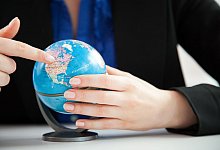 Eine Frau schaut auf einen kleinen Globus im Büro - Christin Klose/dpa-tmn Eine Frau schaut auf einen kleinen Globus im Büro - Christin Klose/dpa-tmn