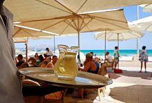 Kellner serviert am Strand einen Wein - Clara Margais/dpa/dpa-tmn