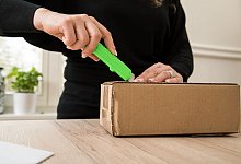 Frau öffnet ein Paket - Christin Klose/dpa-tmn