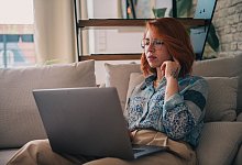 Eine Frau sitzt auf der Couch und nutzt einen Laptop - Zacharie Scheurer/dpa-tmn