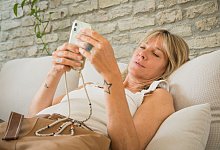 Frau mit Smartphone im Wohnzimmer - Christin Klose/dpa-tmn