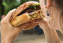 Frau isst einen Burger - Christin Klose/dpa-tmn Frau isst einen Burger - Christin Klose/dpa-tmn