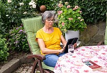 Eine Seniorin sitzt mit einem Tablet im Garten - Benjamin Nolte/dpa-tmn