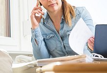 Eine Frau telefoniert und liest Unterlagen durch - Christin Klose/dpa-tmn