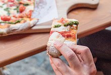 Person isst eine Pizza - Robert Günther/dpa-tmn