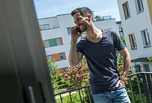 Mann telefoniert auf einem Balkon - Christin Klose/dpa-tmn