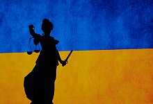 Eine Justitia-Figur vor der ukrainischen Flagge - Sebastian Gollnow/dpa/dpa-tmn