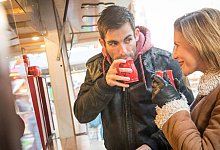 Ein Mann und eine Frau trinken Heißgetränk auf Weihnachtsmarkt - Christin Klose/dpa-tmn