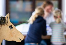 Ein Elternteil sitzt mit seinen Kindern an einem Tisch - Guido Kirchner/dpa/dpa-tmn