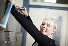 Junge Frau traegt Zeitungen aus - Christin Klose/dpa-tmn