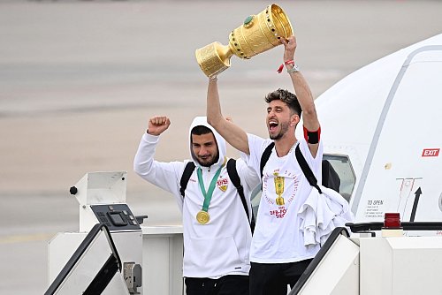 Hoch die Hände: Kapitän Atakan Karazor steigt mit dem Pokal aus dem Flugzeug. - © Marijan Murat/dpa