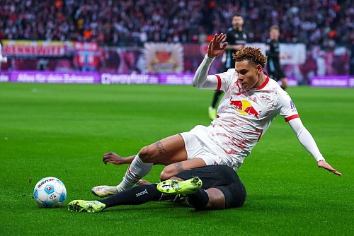Leipzigs Antonio Nusa geht im Zweikampf mit Derrick Köhn zu Boden. - © Jan Woitas/dpa