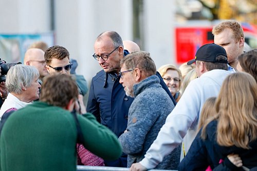 Bundeskanzler Friedrich Merz (CDU) wird von Bürgern beim Bürgergespräch begrüßt. - © Thomas Banneyer/dpa