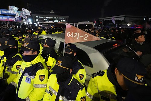 Polizisten vor dem Parlament schützten Militärfahrzeuge. - © Lee Jin-man/AP/dpa