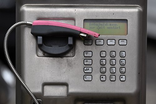 Ein abgebrochener Telefonhörer liegt in der Halterung eines deaktivierten Fernsprechers. - © Federico Gambarini/dpa