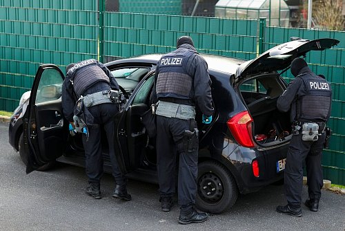 Nach Sonderzug-Gewalt: Polizeibeamte durchsuchen mehrere Pkw vor einem Wohnhaus. - © Christoph Reichwein/dpa