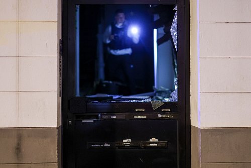 Ein Beamter untersucht Spuren im Hausflur. - © Christoph Reichwein/dpa