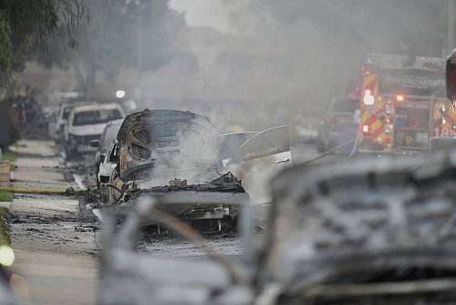 Einsatzkräfte fahren an beschädigten Fahrzeugen am Schauplatz des Absturzes eines Kleinflugzeugs in einem Stadtviertel von San Diego vorbei. - © Gregory Bull/AP/dpa