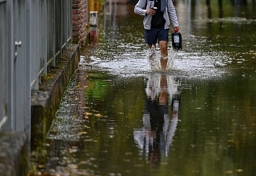 Ein Anwohner einer überfluteten Straße in Frankfurt Oder watet durch das Wasser. - © Patrick Pleul/dpa