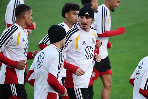 Thiaw (l.) und Woltemade (mit Mütze in der Mitte) laufen beim DFB-Training. - © Christian Charisius/dpa