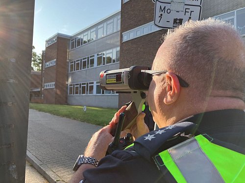 Bei einer Verkehrssicherheitsaktion vor einer Düsseldorfer Grundschule misst ein Polizist die Geschwindigkeit von Autofahrern. - © Volker Danisch/dpa