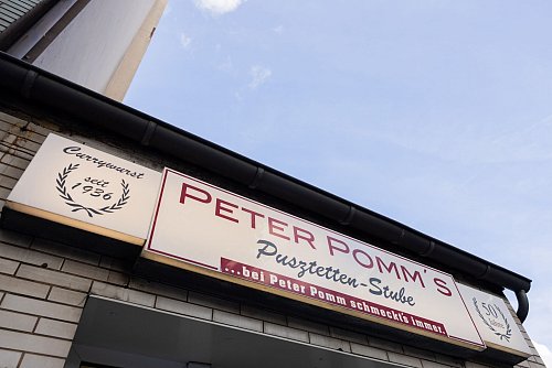 Currywurst seit 1936: Das Schild an «Peter Pomm\'s Pusztetten-Stube» hat alles ins Rollen gebracht. - © Rolf Vennenbernd/dpa