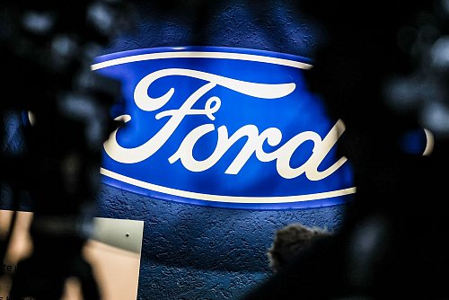 Ein beleuchtetes Firmenschild des Autobauers Ford leuchtet am Rande einer Betriebsversammlung am Standort Köln. - © Christoph Reichwein/dpa