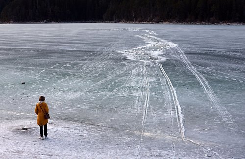 Eine Frau steht am Ufer des zugefrorenen Eibsees, nahe der Stelle an der am Nachmittag mehrere Menschen im Eis eingebrochen waren. - © Karl-Josef Hildenbrand/dpa