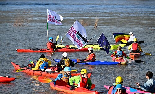 «Kein Rassismus»: Wassersportler demonstrieren auf dem Rhein. - © Roberto Pfeil/dpa