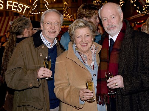 Die Schauspieler Joachim Hermann Luger (Hans Beimer, links) und die Schauspieler Marie-Luise Marjan (Mutter Beimer) und Bill Mockridge (Erich Schiller, rechts) posieren in der Außenkulisse mit Sektgläsern nach der Live-Ausstrahlung der 1559. Folge im Dezember 2015. - © picture alliance / dpa