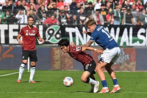 Zweikampf um den Ball: Hayate Matsuda (Hannover 96) wird von Joel Grodowski (Arminia Bielefeld) bedrängt. - © Swen Pförtner/dpa