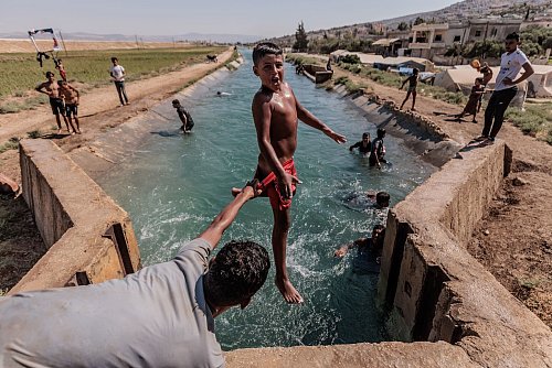 Das Foto des dpa-Fotografen Anas Alkharboutli zeigt syrische Jugendliche bei einer Abkühlung von der Hitze. - © Anas Alkharboutli/dpa