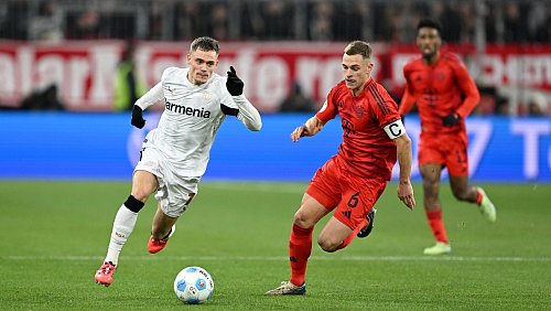 Nationalmannschafts-Kollegen im rasanten Duell: Leverkusens Florian Wirtz (l) und Bayerns Joshua Kimmich. - © Sven Hoppe/dpa