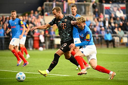 Bayerns Harry Kane (l-r) behauptet den Ball gegen Kiels Finn Porath. - © Gregor Fischer/dpa